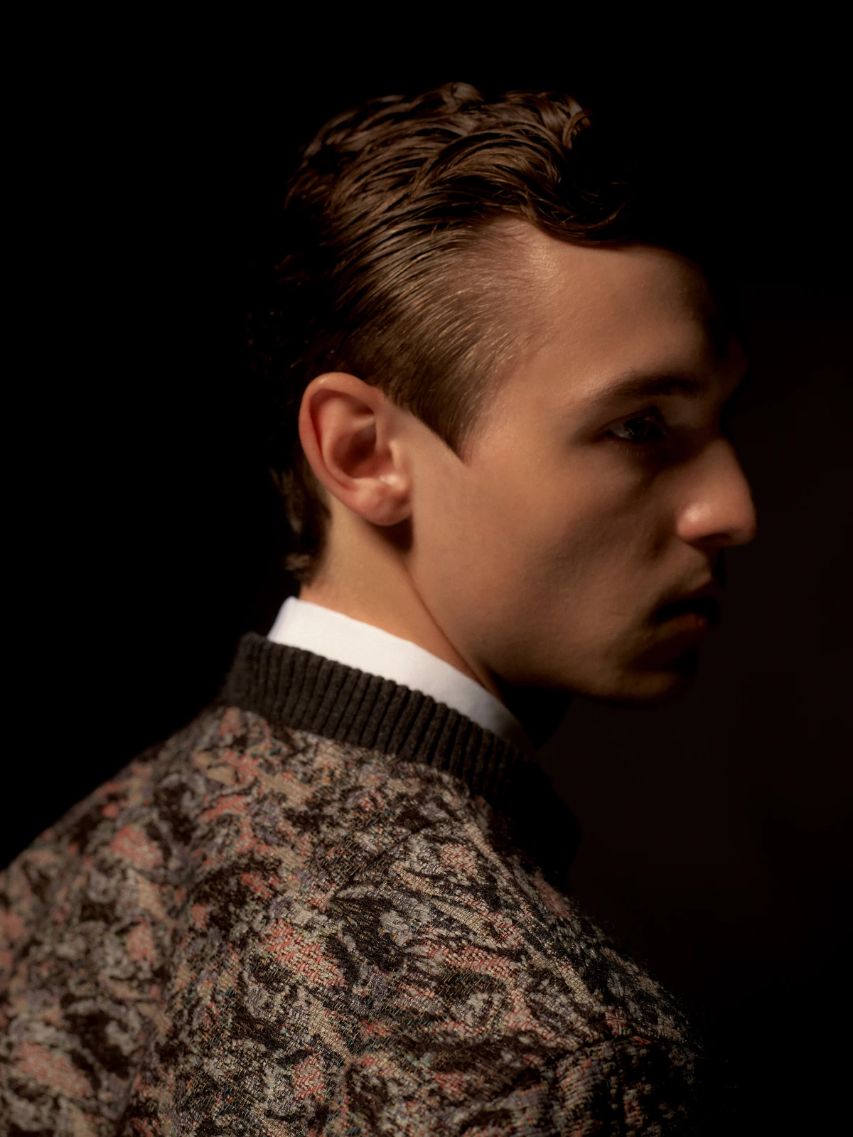 Moody side portrait of young man in patterned knitwear for Dior fashion campaign