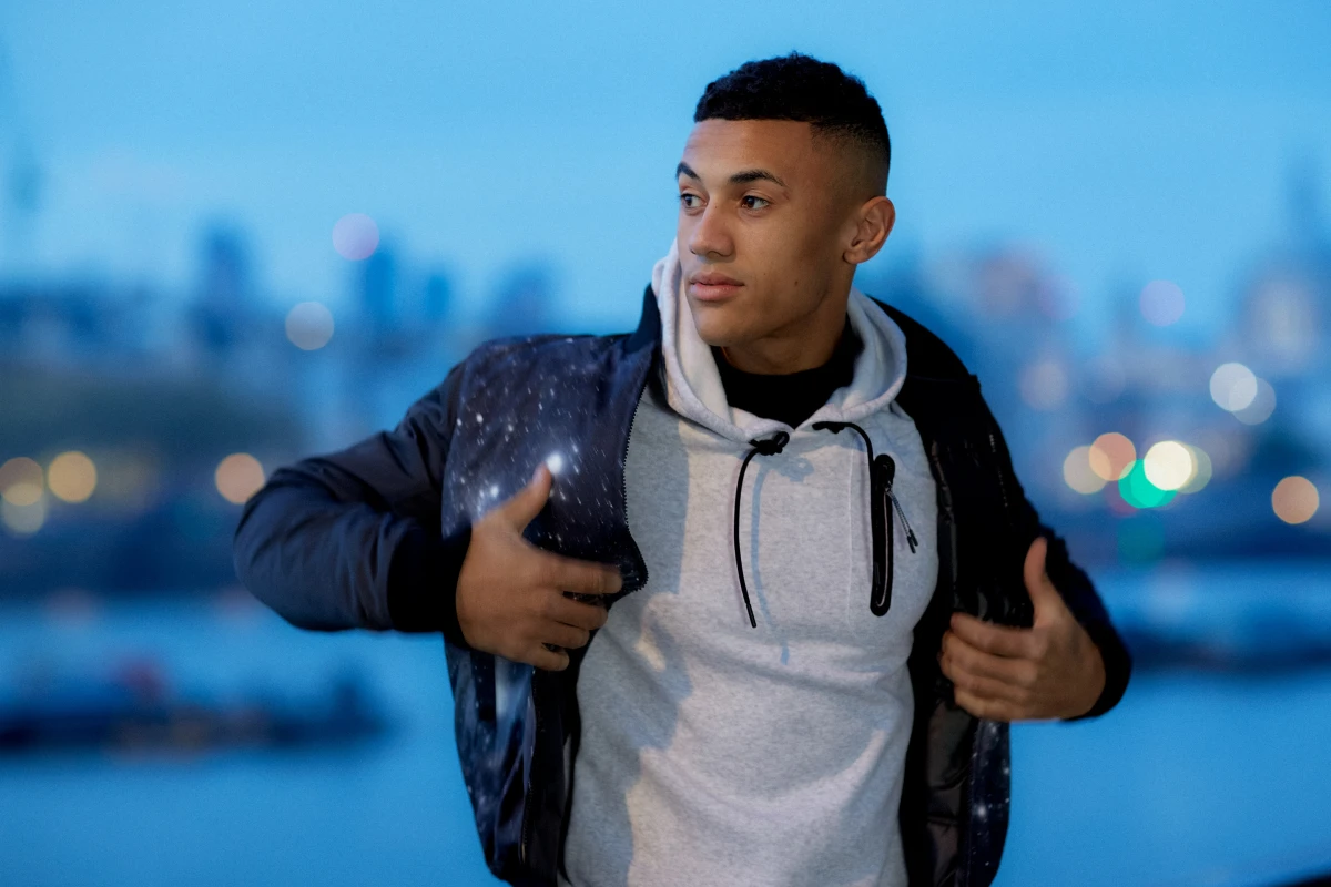 Young man with backpack in hoodie at blue hour waterfront for Adidas commercial sportswear campaign