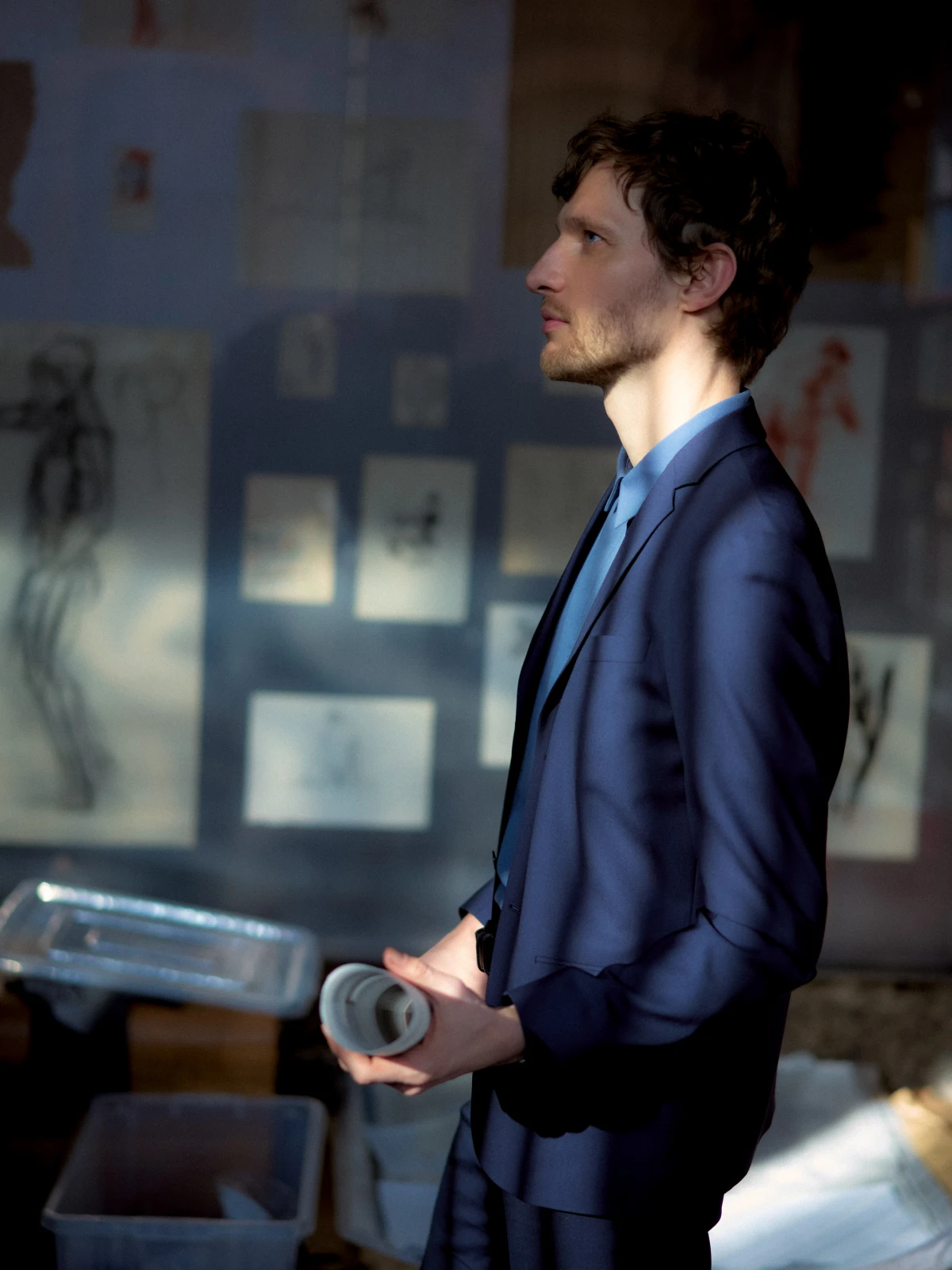 Man in blue suit holding cup in studio office light for RCR Architects editorial portrait