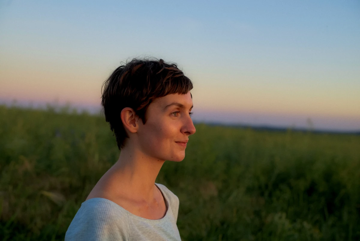 Short-haired person standing in open field at dusk for EON natural energy lifestyle campaign